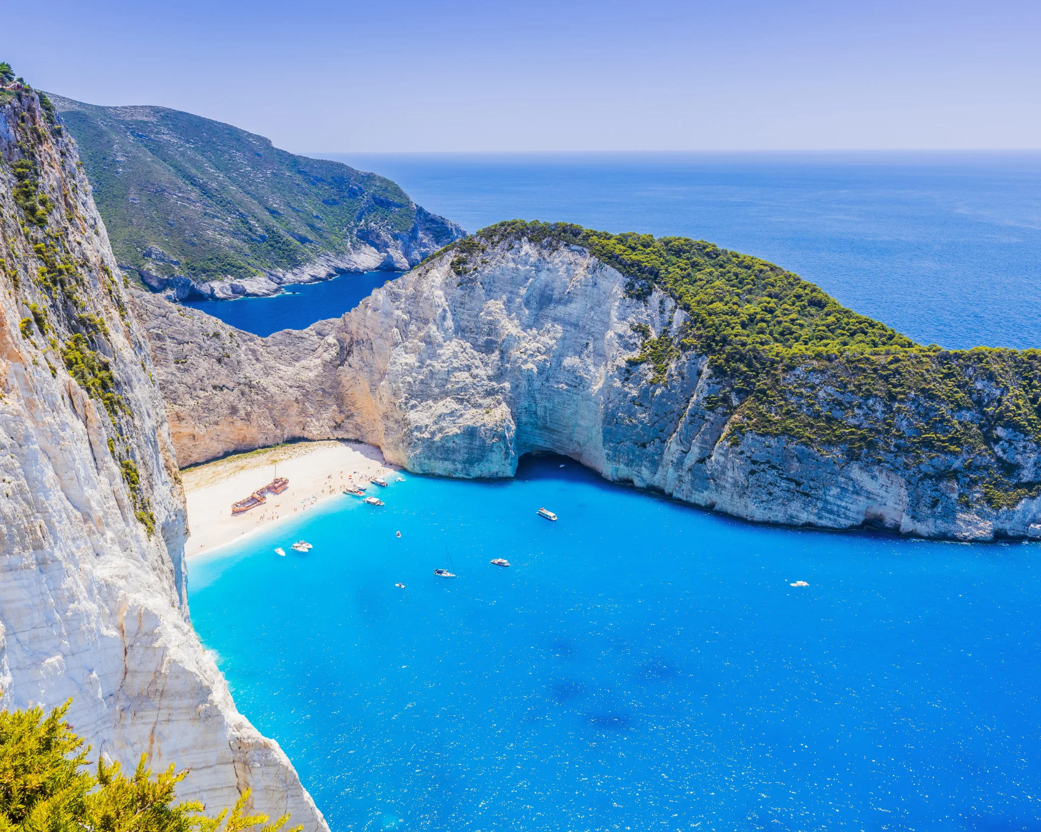 A Navagio-öböl türkiz vize, fehér sziklái és csónakok Zakynthoson